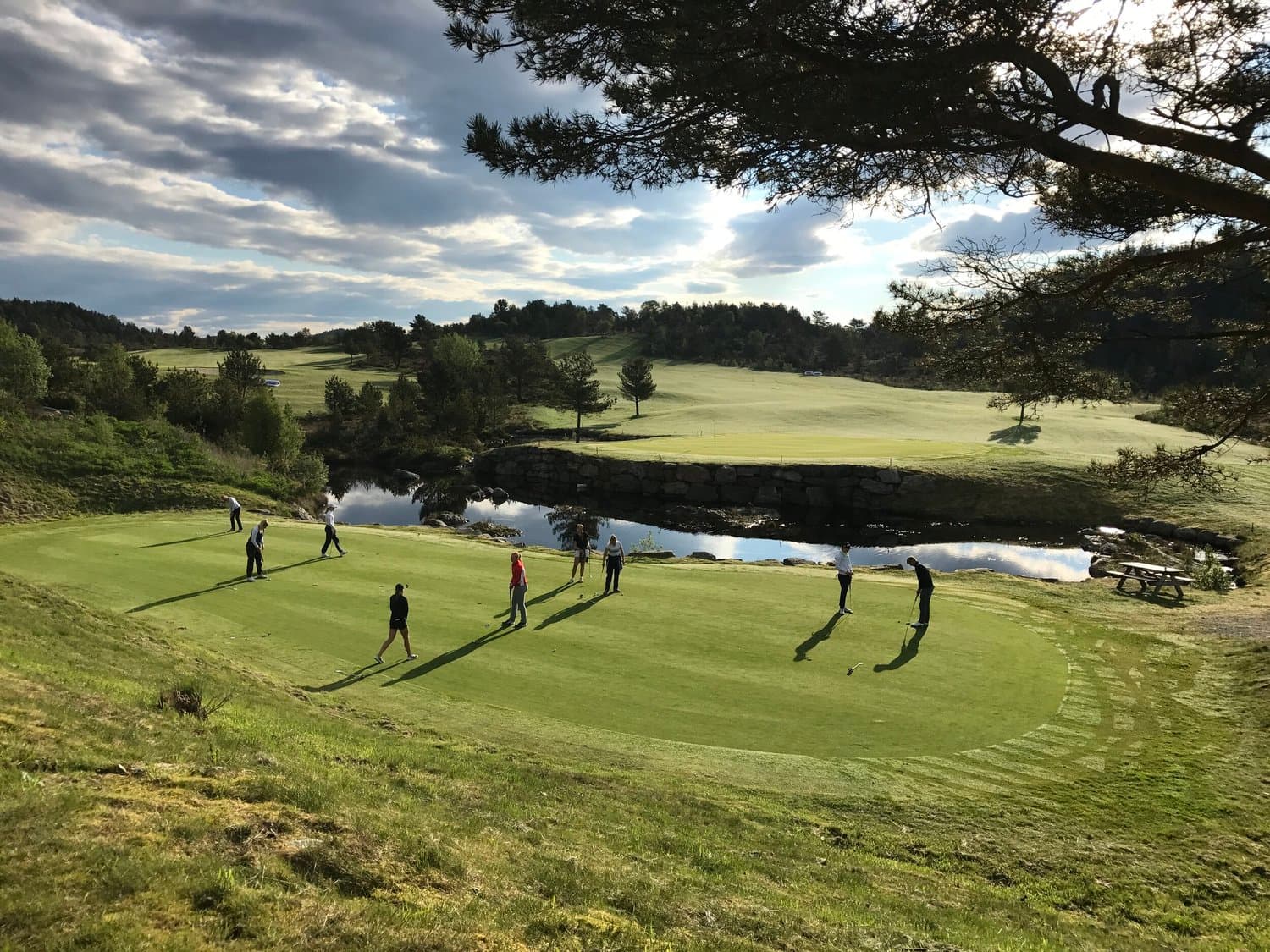 Green ved vannet en dag med dramatisk himmel i Sveio Golfpark